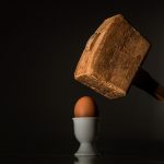 Ein Hammer schwebt über einem Ei